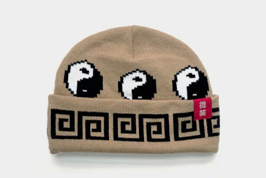 A brown beanie with yin yang symbols and spiral print.