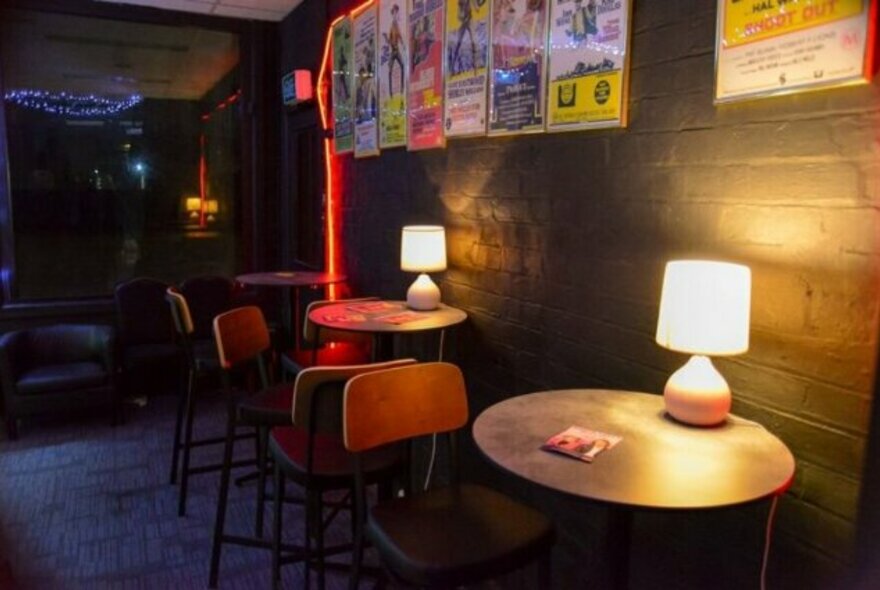 Small round table with lamps and chairs set against a wall in an intimate lounge environment.