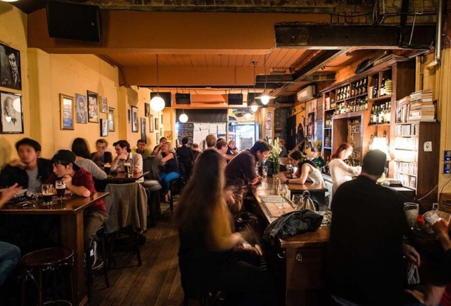 People seated at tables and at the bar of an Irish pub.