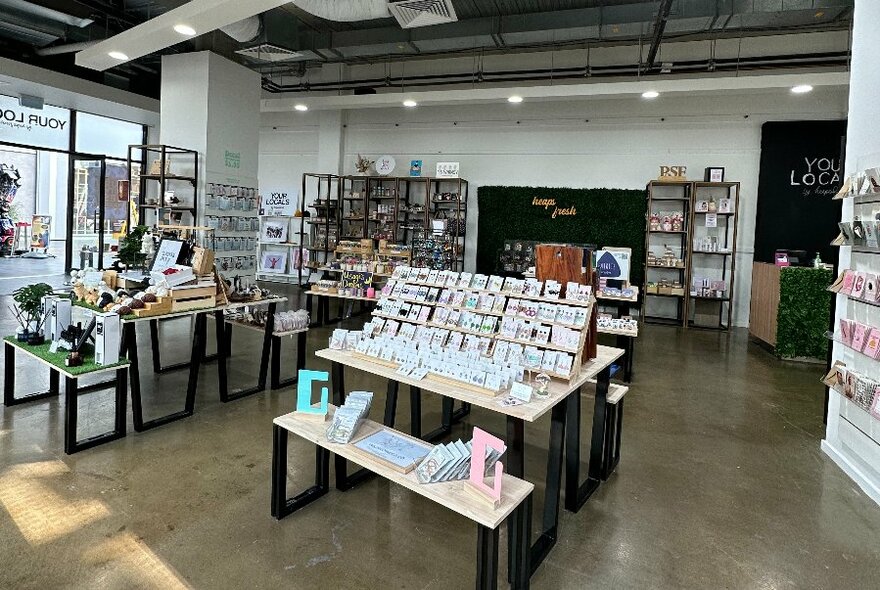 Interior of a retail space with lots of different items on display on tables and shelves.