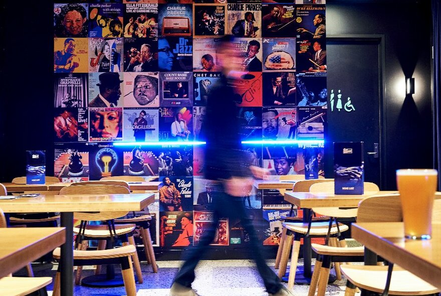 Person walking through a bar set with tables.