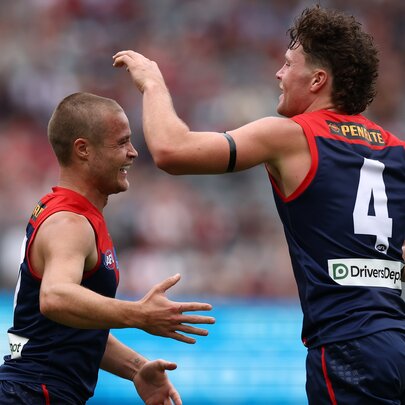 Two AFL football players clapping hands during a match.