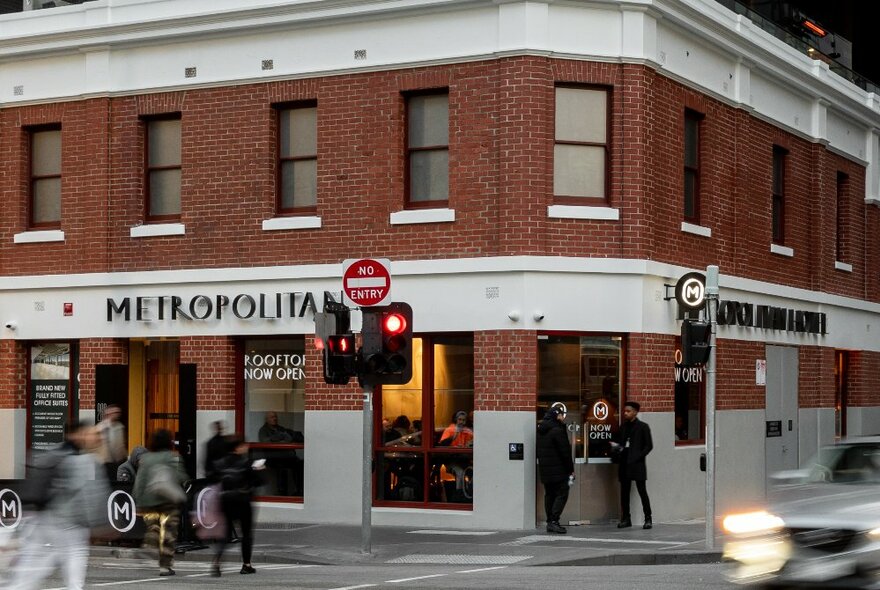 Metropolitan Hotel exterior with people standing outside with streetlights and signage.