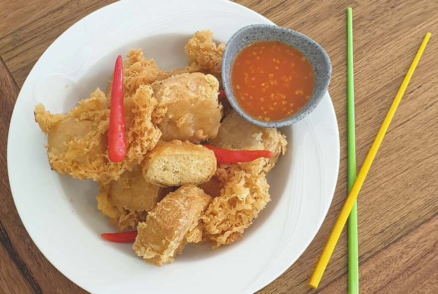 Plate with chopsticks, sauce and fried bean curd.