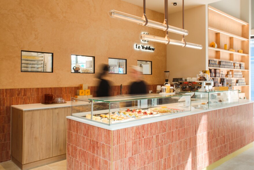 A peach coloured counter with small cakes on display in a cafe.