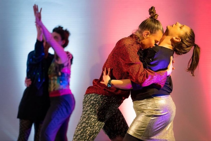 Two couples dancing close together on a stage, part of an improvised theatre piece.
