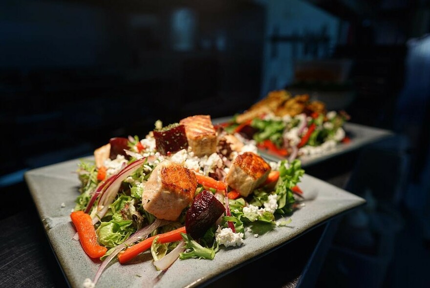 Square platters with salmon and salad.