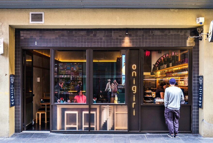 A man is ordering food from a cafe's window.