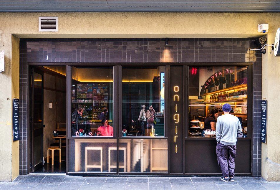 A man is ordering food from a cafe's window.