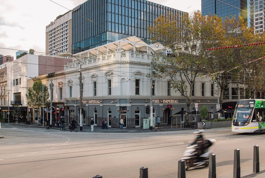 The exterior of a grand white corner pub in the city.