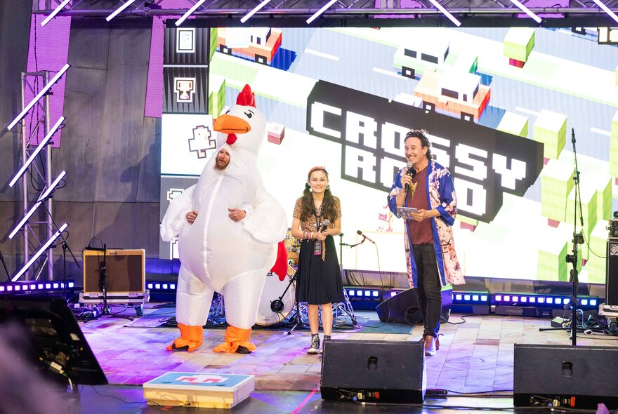 Performers on stage including someone dressed as a large chicken.