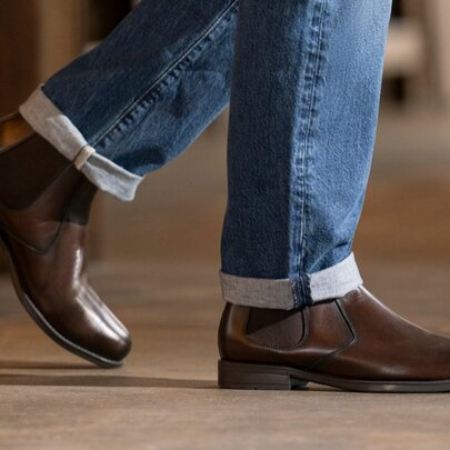Lower half of legs wearing jeans and dark brown leather boots.