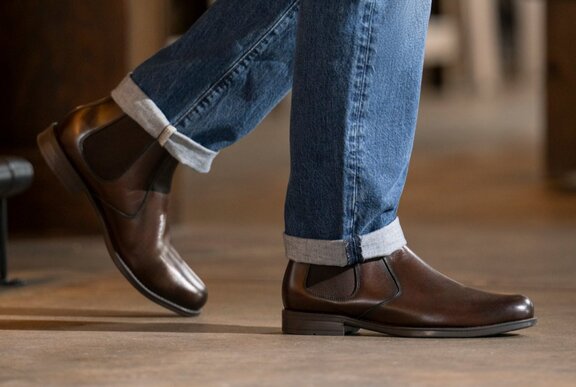 Lower half of legs wearing jeans and dark brown leather boots.