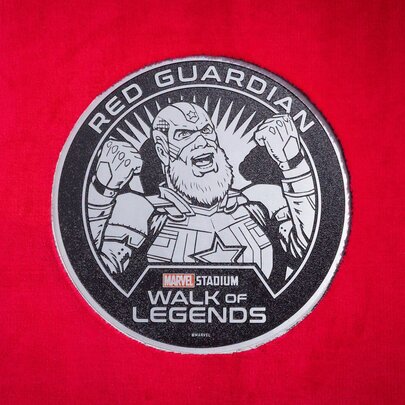 Circular plaque of the Marvel Red Guardian character embedded in the concourse in the Marvel Stadium Walk of Legends.