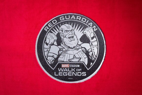 Circular plaque of the Marvel Red Guardian character embedded in the concourse in the Marvel Stadium Walk of Legends.