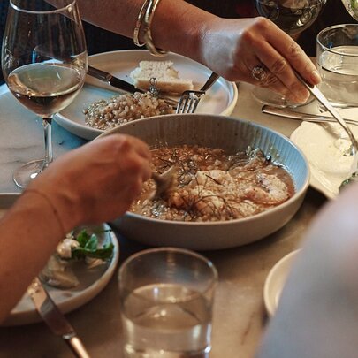 A busy table setting with a large share plate of stew in the middle of four diners