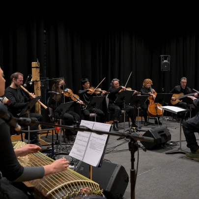 Members of the Australian Art Orchestra with their instruments, playing in a large room
