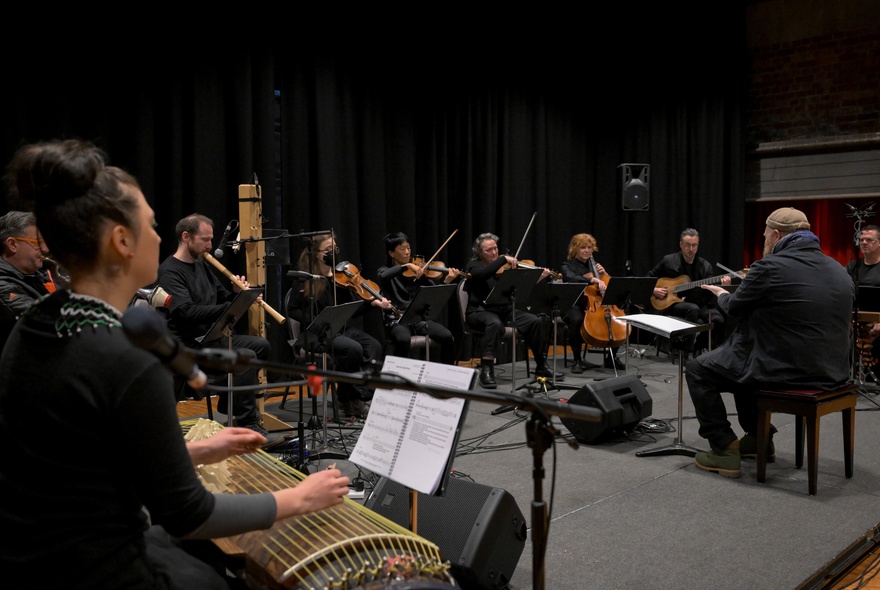 Members of the Australian Art Orchestra with their instruments, playing in a large room
