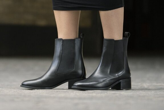 Lower section of legs wearing short black ankle boots.