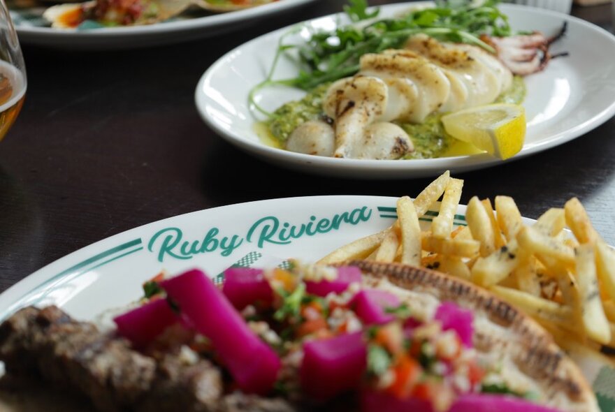 Plates of food on a dark tabletop in a restaurant.