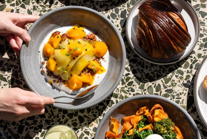 Looking down on a table with dishes including pastries and fruits.