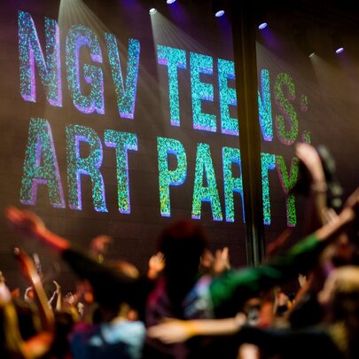 Crowd dancing under signage in dark-lit venue.
