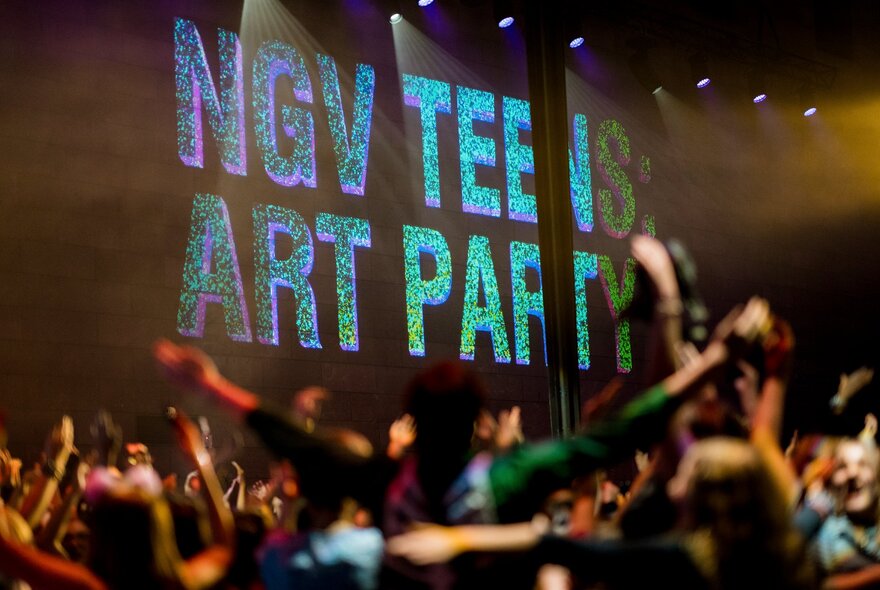 Crowd dancing under signage in dark-lit venue.
