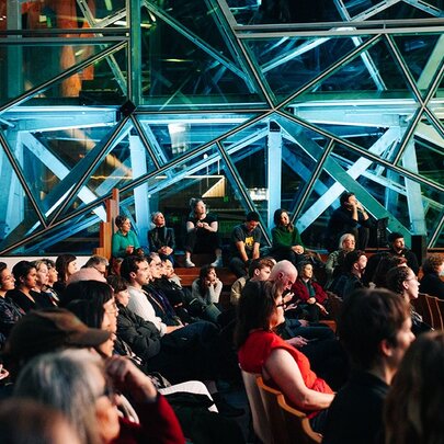 People gathered listening to a lecture at The Edge in Fed Square. 