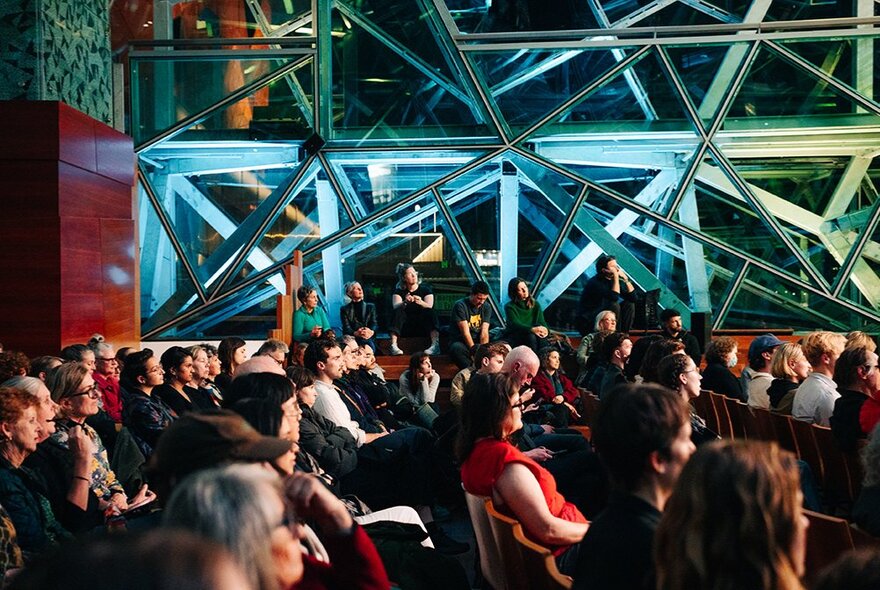 People gathered listening to a lecture at The Edge in Fed Square. 