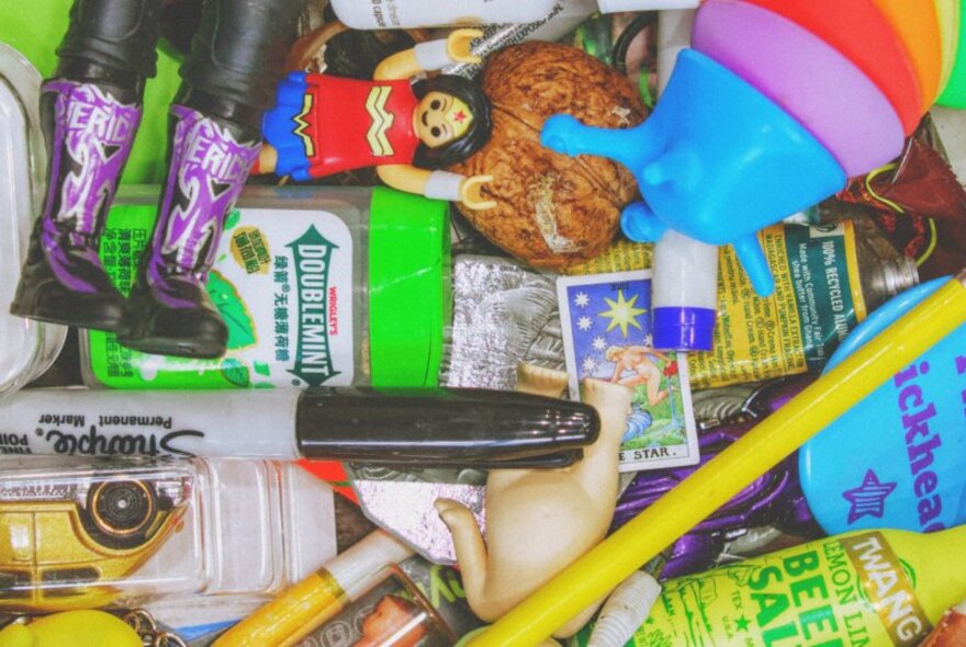 Top down view of a jumble of small miscellaneous items, including miniature toys, a marker, and small plastic figurines.