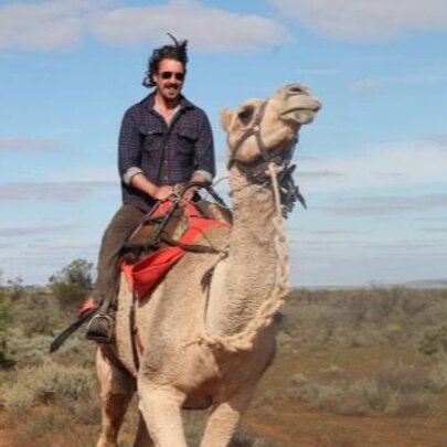 A man riding a camel in outback Australia.