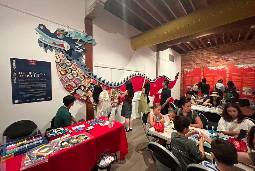 Children at tables in a workshop with a Chinese dragon on display.