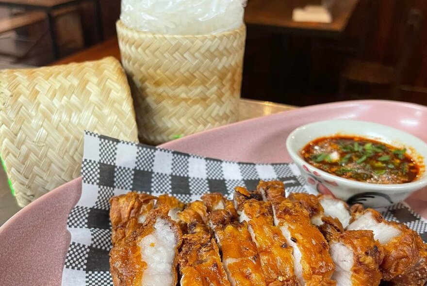 Plate of sliced crispy pork with a small bowl of dipping sauce. 