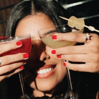 Woman hiding her eyes with two cocktails.
