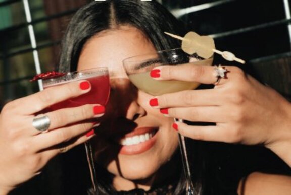 Woman hiding her eyes with two cocktails.