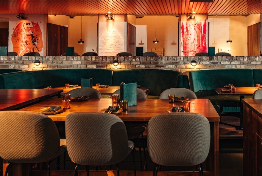 The interior of The George on Collins with dining tables and soft upholstered chairs, a central bar area in the background.