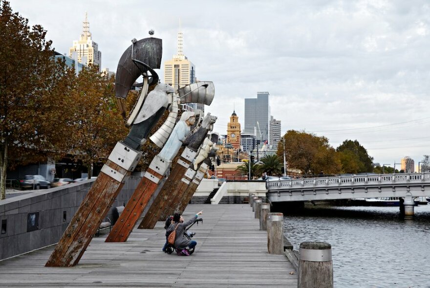 People sitting under the tall figureheads of the Constellation artwork.