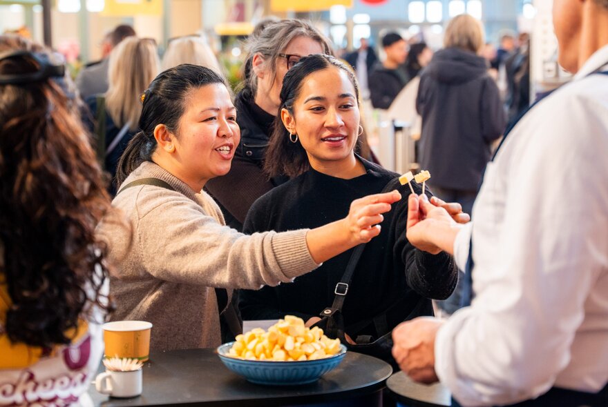 People being offered tasting samples on cocktail sticks.
