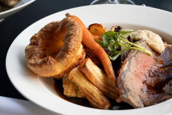 Plate of roast meat and vegetables with Yorkshire pudding.