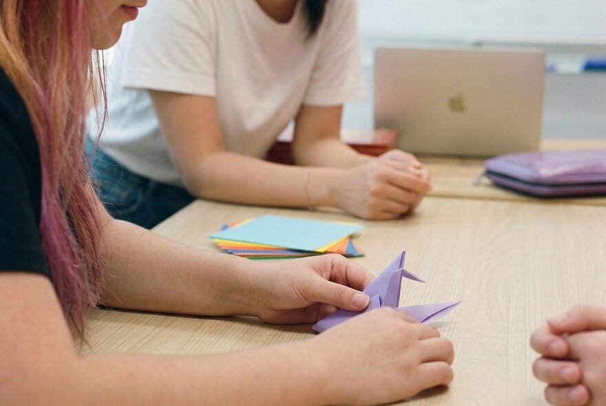 Teens making origami in a workshop setting. 
