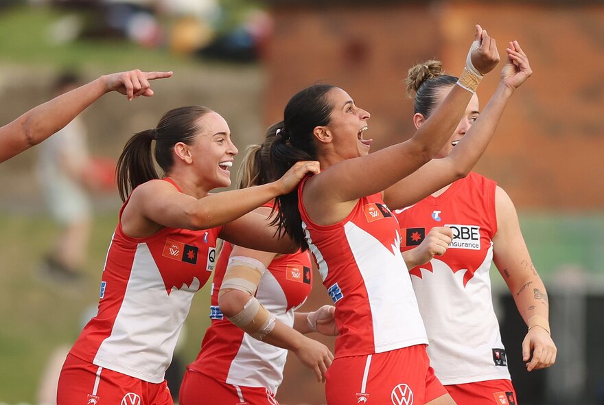 Players from the Sydney Swans celebrating on the field during an AFLW match.