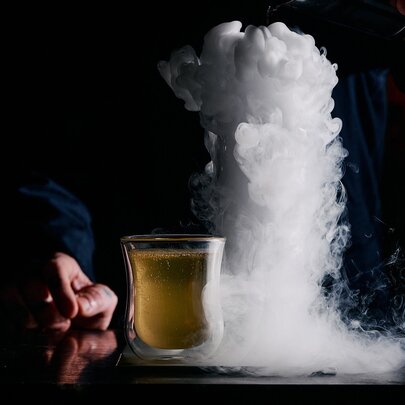 A cocktail in a stone bowl with gelato on top.