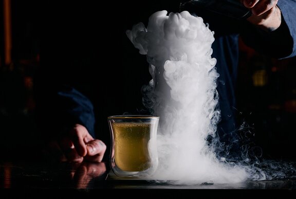 A cocktail in a stone bowl with gelato on top.