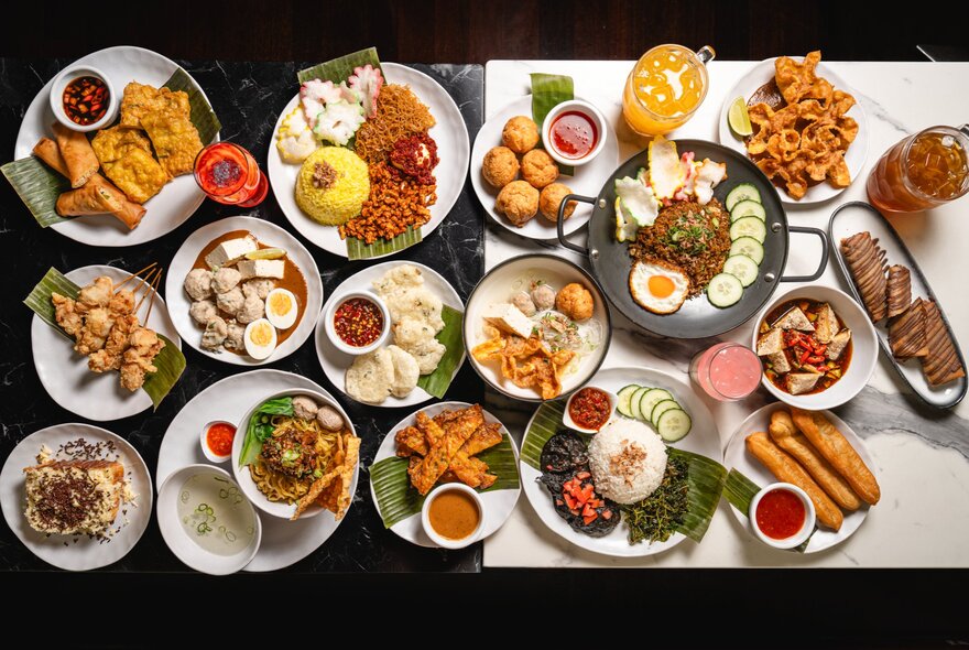 Overhead view of multiple Indonesian dishes of food including fried and salad dishes.