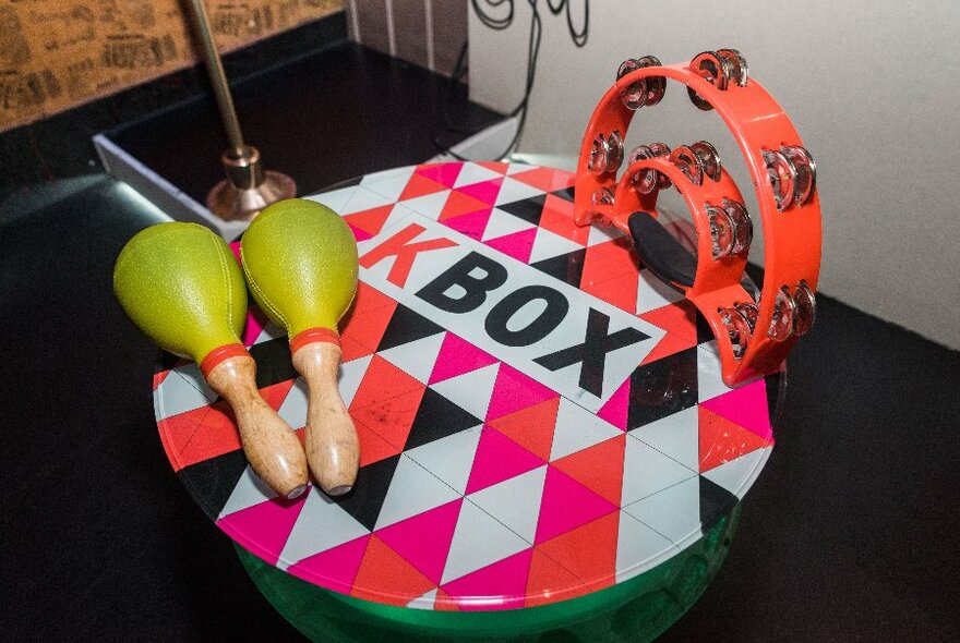 Neon-coloured instruments including a tambourine, maracas and drum.