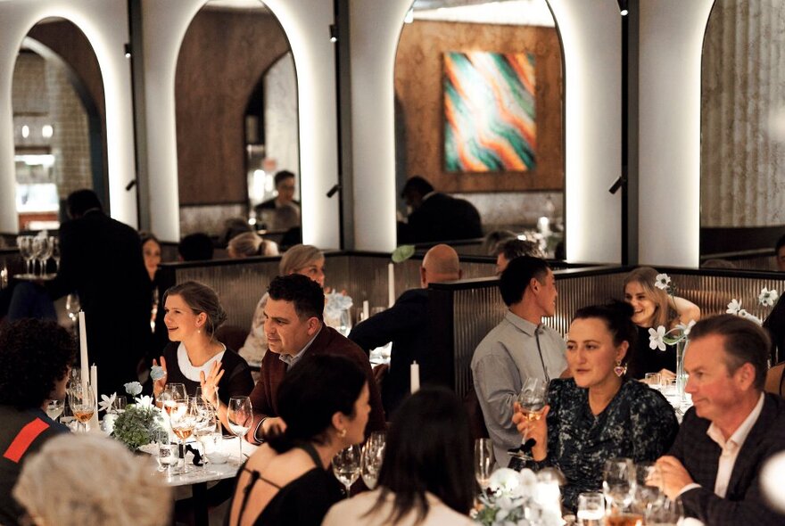 People all seated in formal attire in an elegant restaurant setting. 