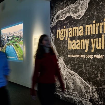 People passing an exhibition sign in a museum.