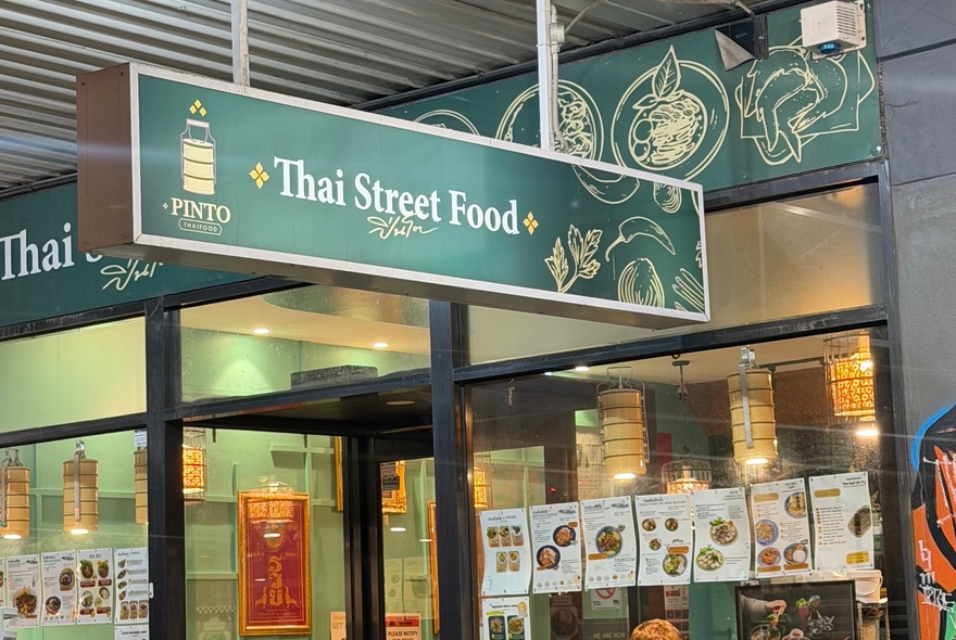 Thai restaurant facade with signage and window posters.