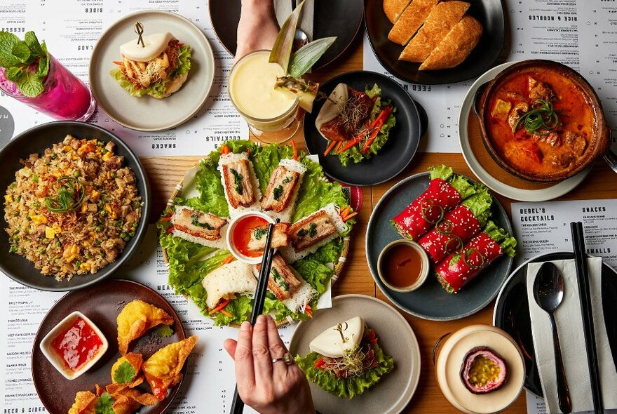 A table set with colourful Vietnamese dishes and cocktails. 