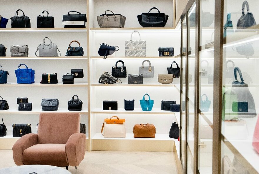 Store shelving units filled with multicoloured designer handbags.